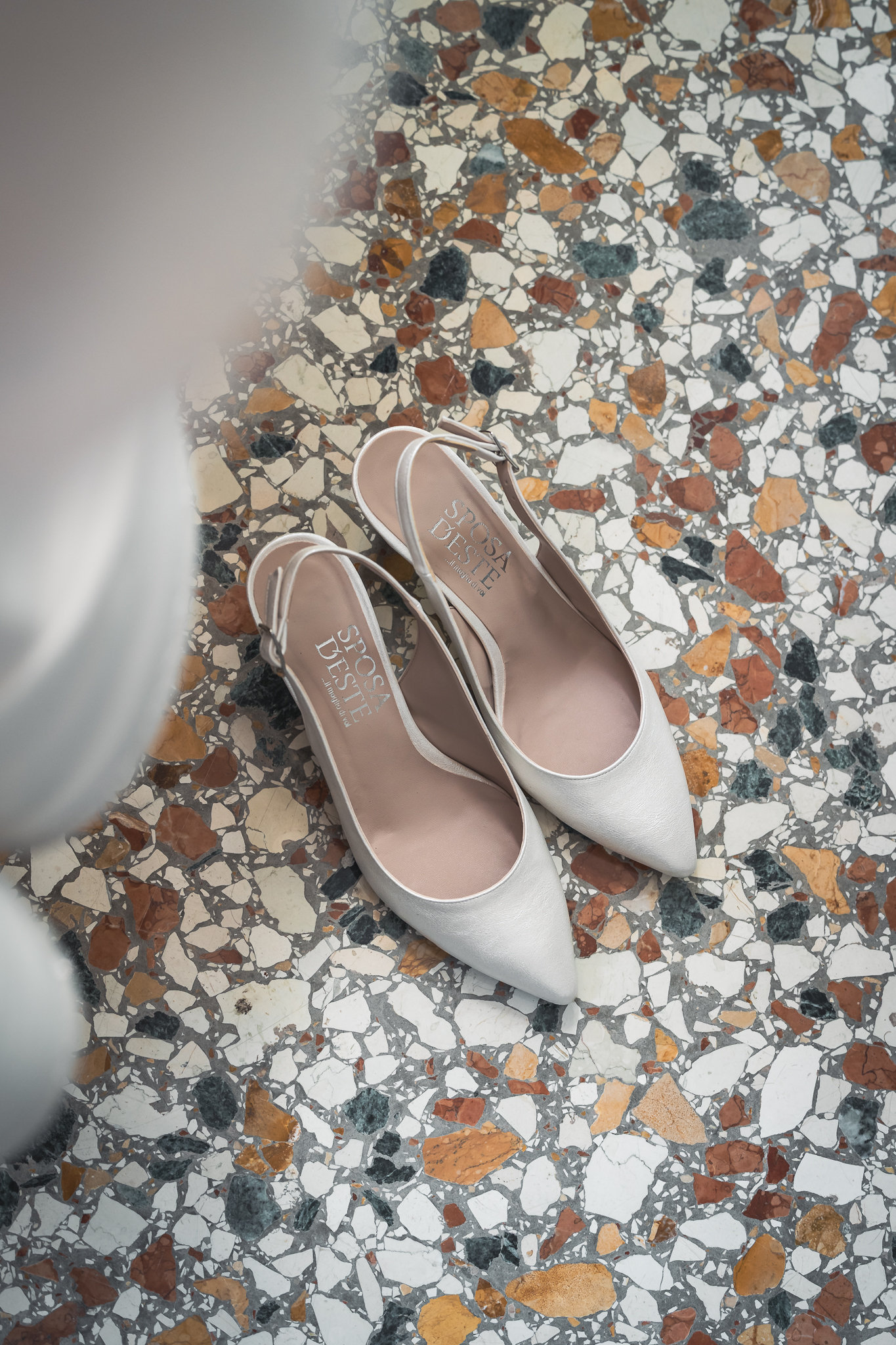 Le scarpe della sposa fotografate da vicino sul pavimento a terrazzo