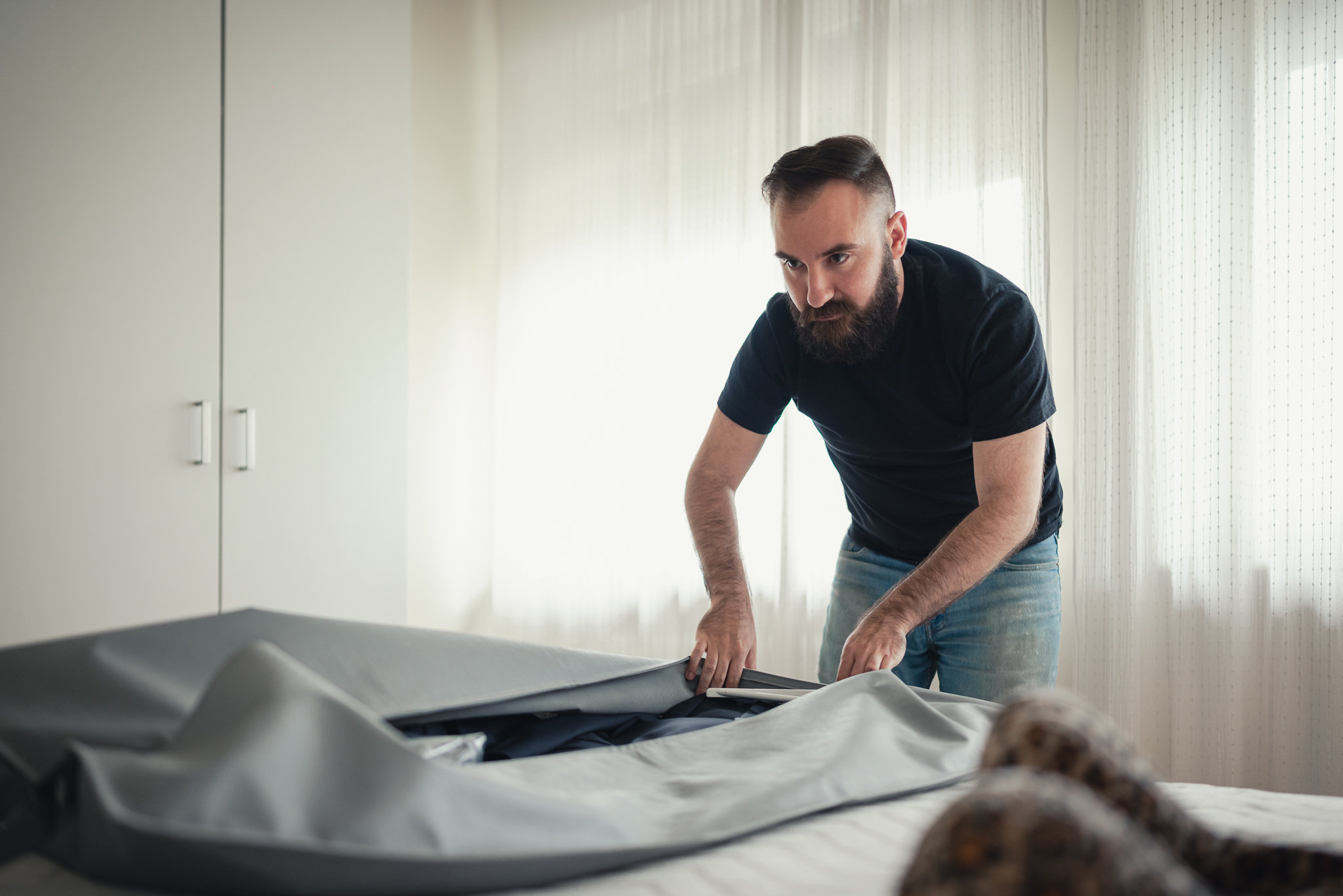 Salvatore piega la giacca da sposo sul letto prima di vestirsi
