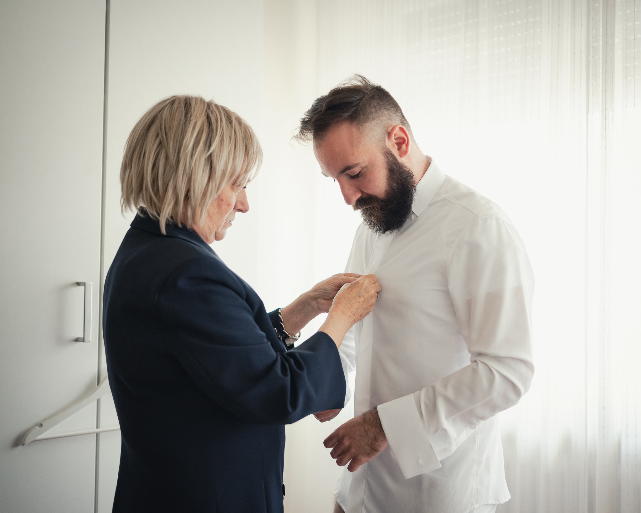 La madre di Salvatore lo aiuta ad abbottonare la camicia
