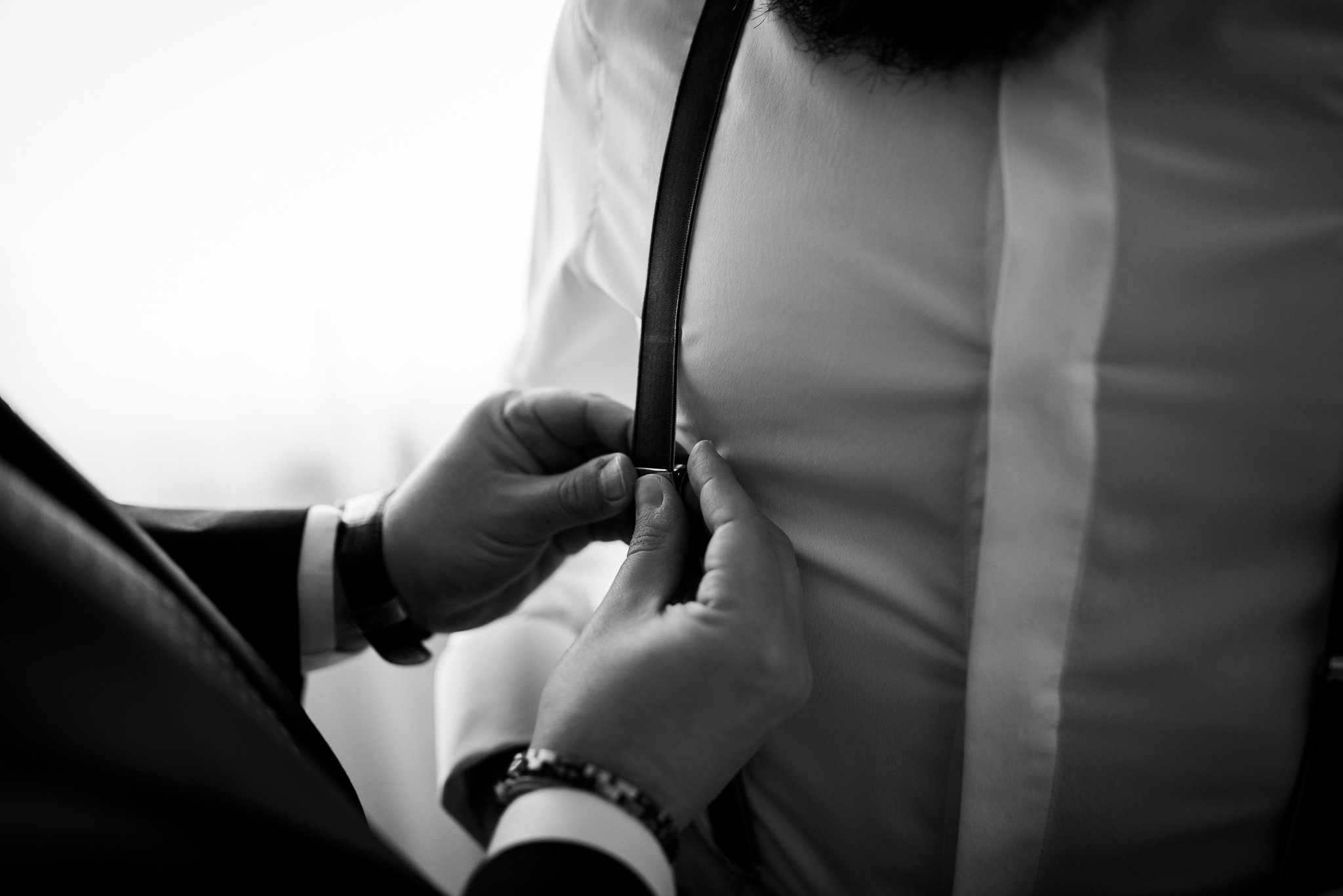Dettaglio in bianco e nero delle mani che sistemano il polsino