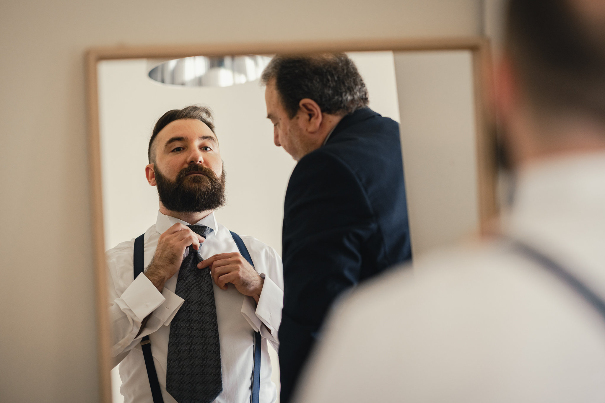Salvatore annoda la cravatta davanti allo specchio, aiutato dal padre