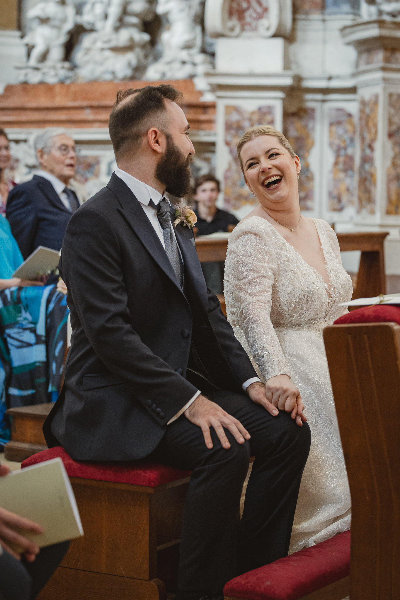 Gli sposi si scambiano uno sguardo complice e ridono, seduti all'altare