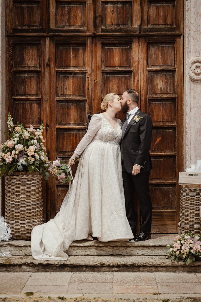Il bacio degli sposi sul portale della chiesa, ancora avvolti dal riso