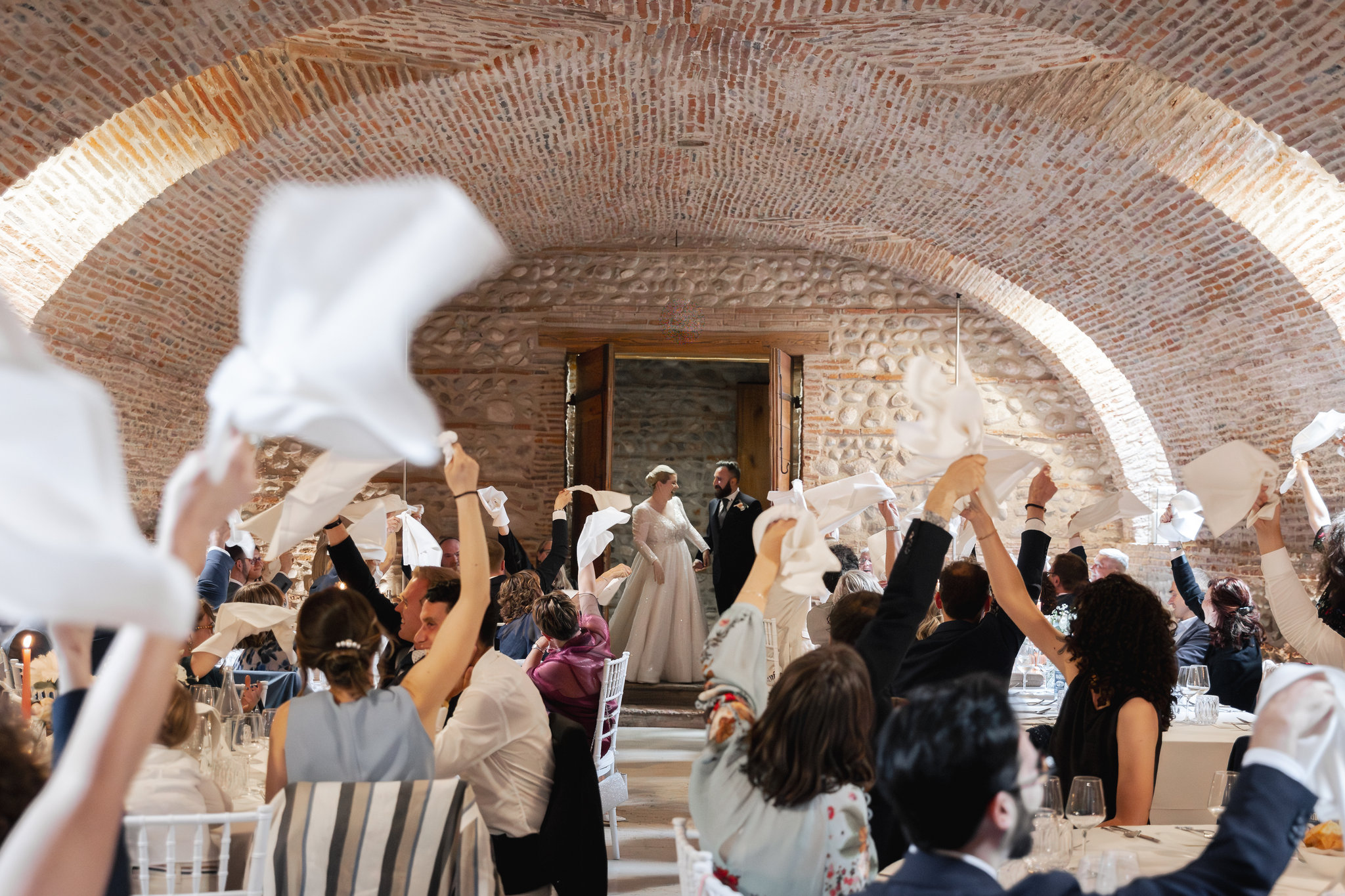 Gli invitati sventolano i tovaglioli al passaggio degli sposi