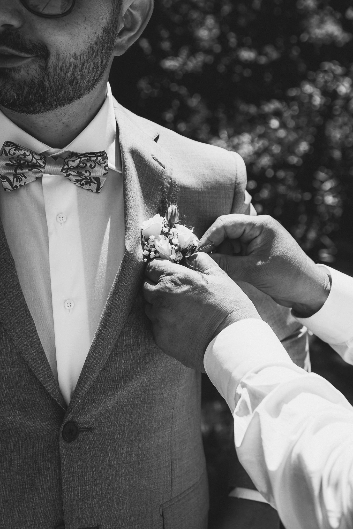La boutonnière viene appuntata alla giacca dello sposo in giardino