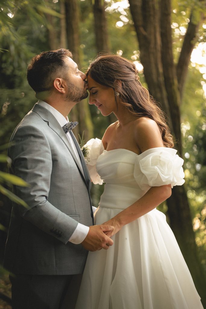Michele bacia Marta sulla fronte nella luce dorata del bosco